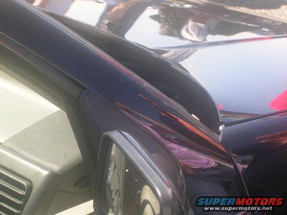 Dark colored vehicle fender and door seam with reflection of people