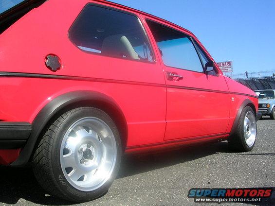 Red VW Golf GTI parked next to another car, with stadium seating in the background