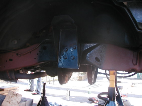 Underside of a vehicle frame with suspension parts, jack stands supporting it