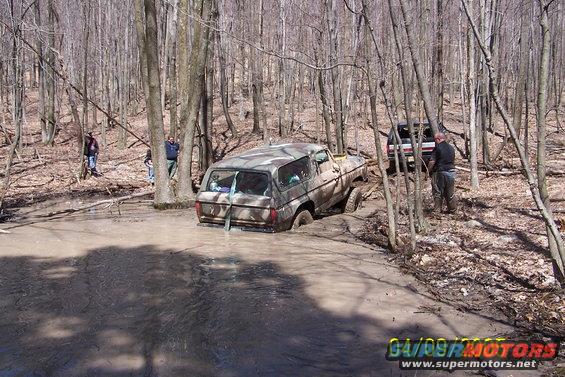 Muddy 1979 Ford Bronco stuck in a creek bed with another SUV behind it