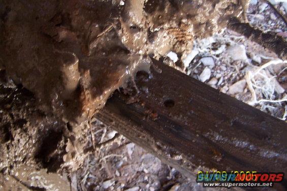muddy ground with a wooden beam and some debris, timestamp 04/09/2005