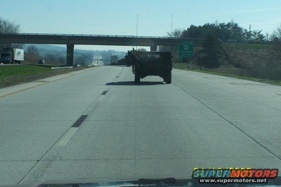 Dark SUV on highway, rear view. Visible traffic and overpass