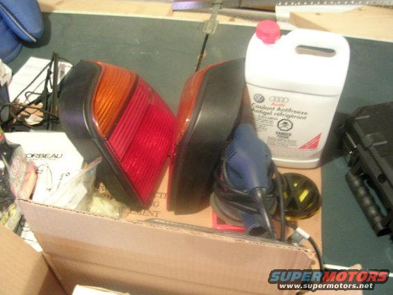Two red and orange car taillights and a jug of Audi coolant