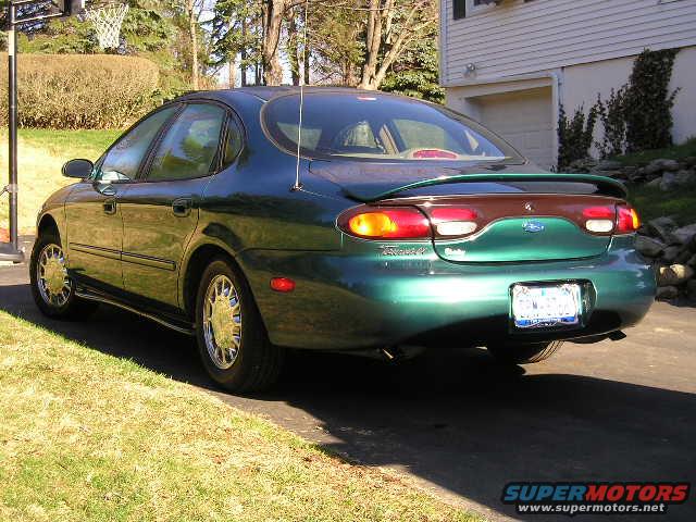 Rear view of a green 1996 Ford Taurus with a spoiler parked on a driveway