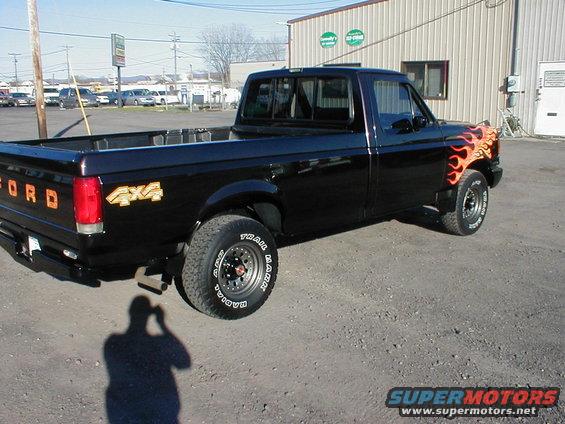 Black pickup truck with orange flame decals on the front fender and '4x4' graphics on the bed