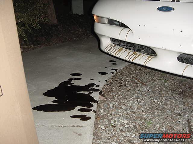 1993 Ford Probe front bumper with oil drips on concrete