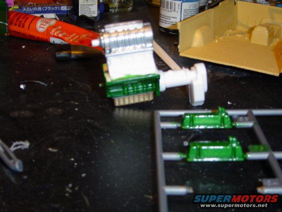 Model engine and green parts on a sprue, with glue tube and model truck bed in background