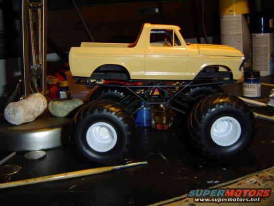 Yellow model truck with large monster truck tires, viewed from the side