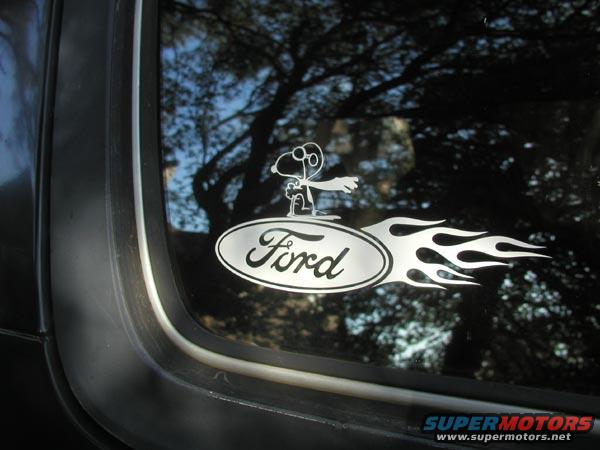 Ford oval logo sticker with Snoopy and flames on a dark tinted window