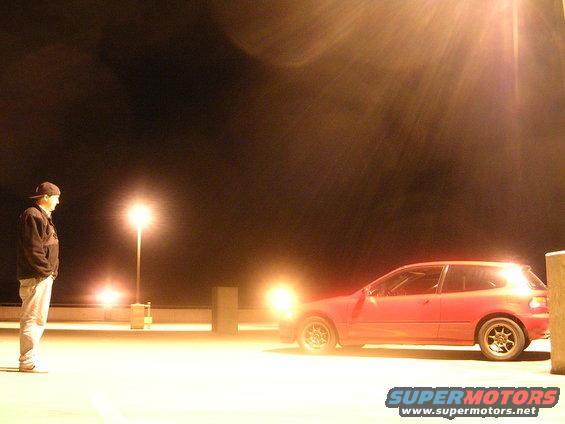 Red hatchback parked at night, side view