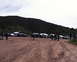 1988 Ford Bronco - A group of off-road vehicles gathered on a dusty track with a large hill dominating the background.
