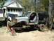 1985 Ford Bronco - A disassembled pickup truck is elevated on jack stands, with another SUV visible in the background.