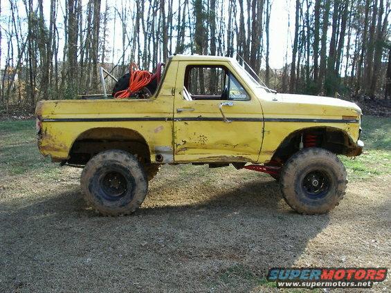 yellow pickup truck with off-road tires and suspension, spare tire and orange rope in bed
