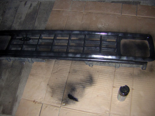 Black grille with horizontal bars and a central emblem, spray paint can nearby