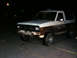 1986 Ford Bronco II - A weathered 1986 Ford Bronco II is parked at night, with visible rust on its body panels.