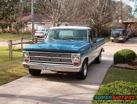 Front view of a blue and white 1968 Ford F-100 pickup truck with a chrome grille and license plate BPY-C82