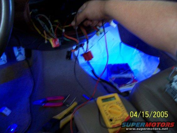 hand working on car wiring with tools and multimeter