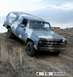 1979 Chevrolet Suburban - A 1979 Chevrolet Suburban with camouflage paint is driven up a dirt hill under a cloudy sky.