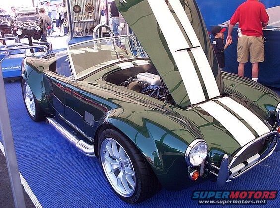 Green AC Cobra replica with hood open, showing engine and side exhaust pipes