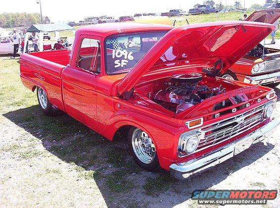 Red Ford pickup truck with hood open, chrome grille, and custom wheels