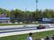 1978 Ford F-250 - A red pickup truck is seen on a drag strip under a clear blue sky.