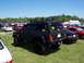 1978 Ford F-250 - A black Jeep Cherokee is parked on a grassy field with other vehicles in the background under a clear blue sky.