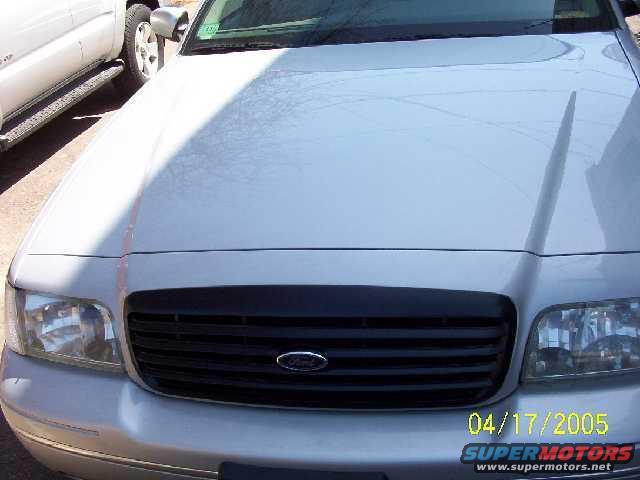 Silver Ford Crown Victoria front grille and headlights, parked next to a white truck