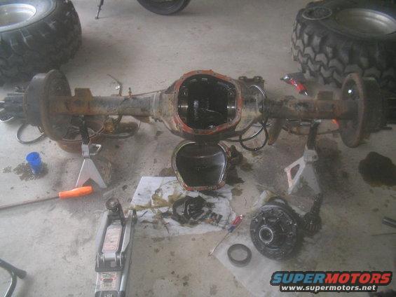 Rusty rear axle assembly with differential cover removed, resting on jack stands
