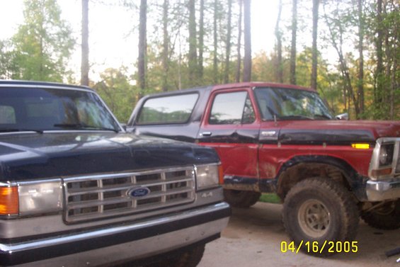 Red 1978 Ford Bronco with black trim and a dark blue Ford truck