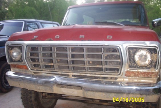 1979 Ford F-150 front grille and bumper, red hood with 'FORD' lettering. Another vehicle is partially visible to the left