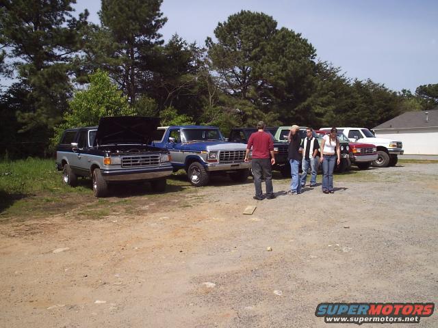 Two-tone gray and black Ford Bronco with hood open, parked on gravel lot
