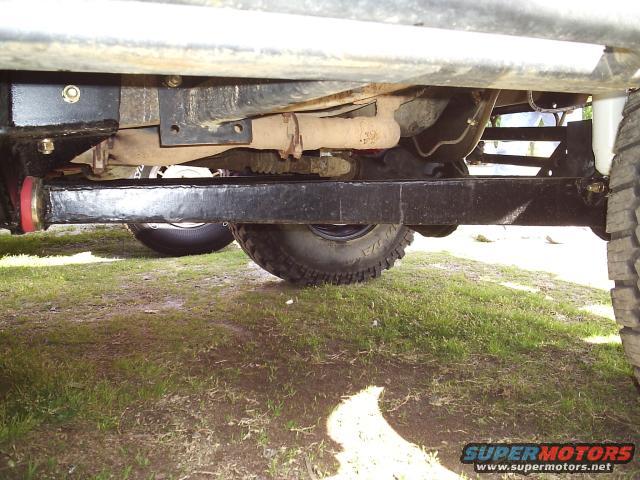 Undercarriage view of a vehicle's modified suspension with large tires and exhaust