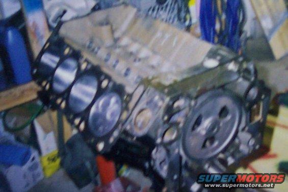 Engine block with cylinders visible, sitting on a stand. Some parts are covered with tape