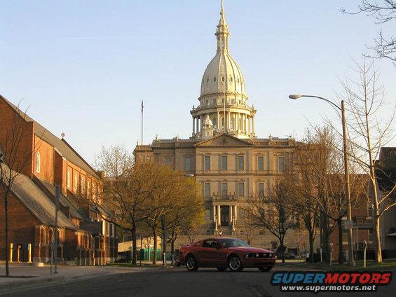 Red 2005 Ford Mustang parked in front of the Michigan State Capitol building