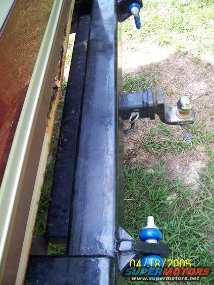 Rusty rear bumper with a black trailer hitch and ball mount