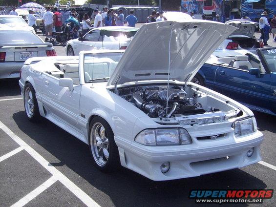 White convertible with hood open, showing engine. Chrome wheels and custom body kit