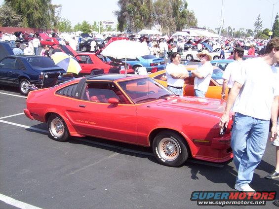 Red 1978 Ford Mustang King Cobra coupe with louvers and black t-top at a car show