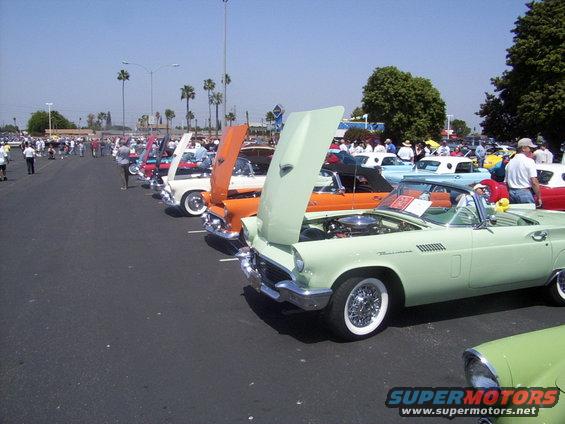 Light green convertible with hood up, parked in a row of classic cars