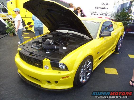 Yellow 2005 Ford Mustang coupe with hood open, showing engine and chrome wheels