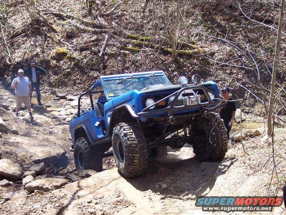 Blue 1974 Ford Bronco with off-road modifications on a rocky trail