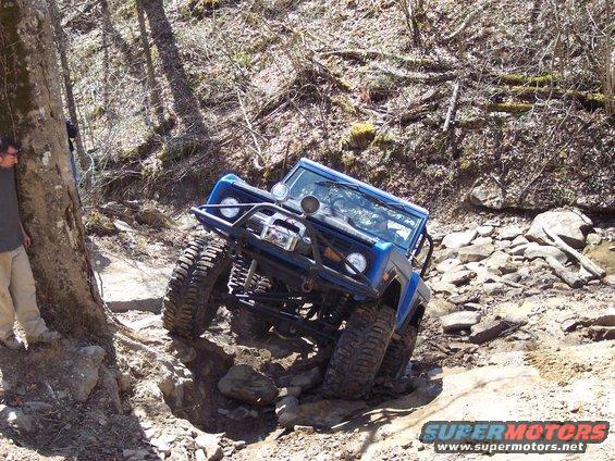 1974 Ford Bronco navigating a steep, rocky trail with large tires and a front brush guard