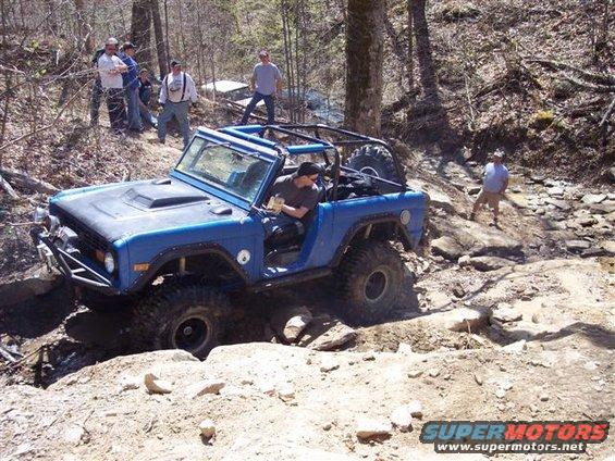 Blue 1974 Ford Bronco off-roading on a rocky trail