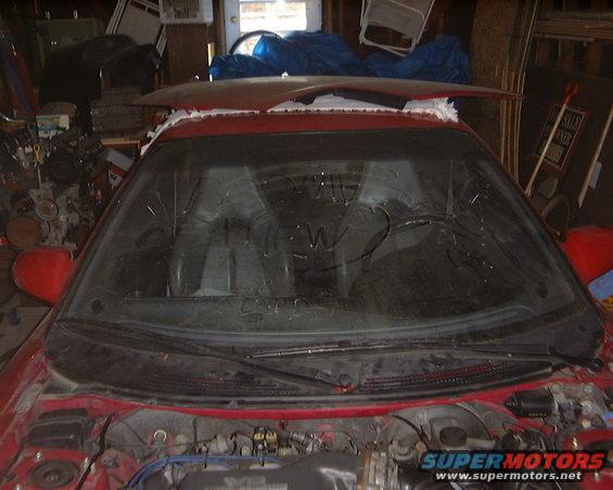 Red car interior with windshield and engine bay visible. Supermotors.net logo on lower right