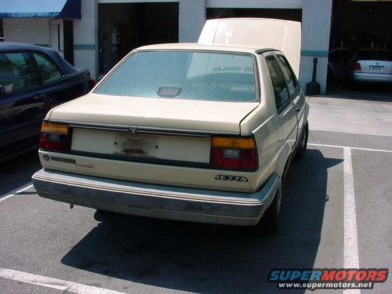 Beige sedan's rear view, hood open. Appears to be a 1988 Volkswagen Jetta