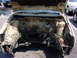 1998 Volkswagen Jetta - The engine bay of a car is shown with the hood open, revealing an empty space where the engine would be. Other vehicles are parked in the b…