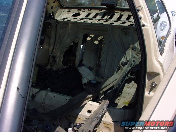 Interior of a car with seats and panels removed, showing the frame and wiring
