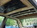 1998 Volkswagen Jetta - The interior ceiling of a car shows exposed insulation and structural elements, with other vehicles visible through the windows.