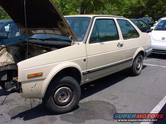 Beige sedan with hood open, missing front bumper. Appears to be a 1984 Volkswagen Jetta