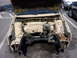 1998 Volkswagen Jetta - The engine bay of a tan car is shown with the hood open, revealing a disassembled front end and engine components.