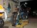 1976 Harley-Davidson Super Glide - A blue motorcycle is secured on a yellow lift in a garage, with a truck visible in the background.